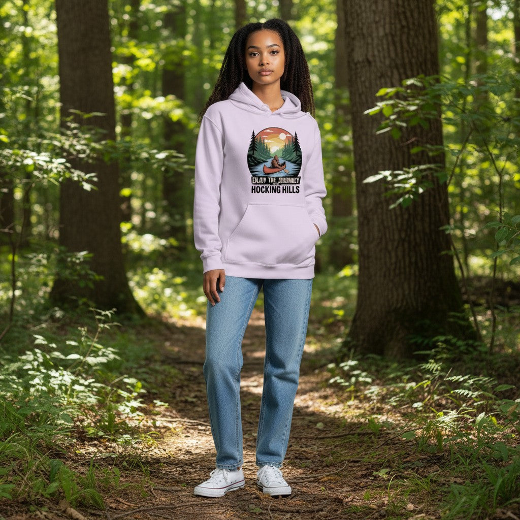 The Hocking Hills Store Enjoy The Journey hoodie in light purple, featuring a graphic of Bigfoot in a canoe on a river with trees and a sunset.