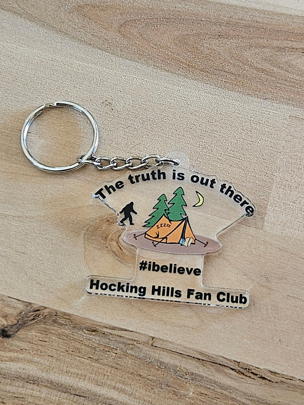 The Hocking Hills Store keychain with Bigfoot, tent, and trees. Features text 'The truth is out there', '#ibelieve', and 'Hocking Hills Fan Club'.