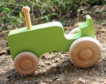The Hocking Hills Store handmade green wooden toy tractor with natural wood wheels and steering column.