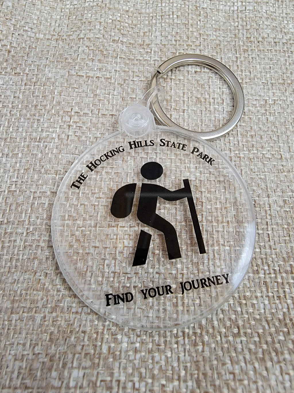 The Hocking Hills Store keychain with a hiker graphic and "Find Your Journey" text. Clear acrylic with black design.