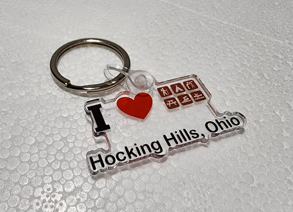 The Hocking Hills Store keychain with clear acrylic, red heart, and icons for camping, hiking, and kayaking. Text reads 'I Love Hocking Hills, Ohio'.