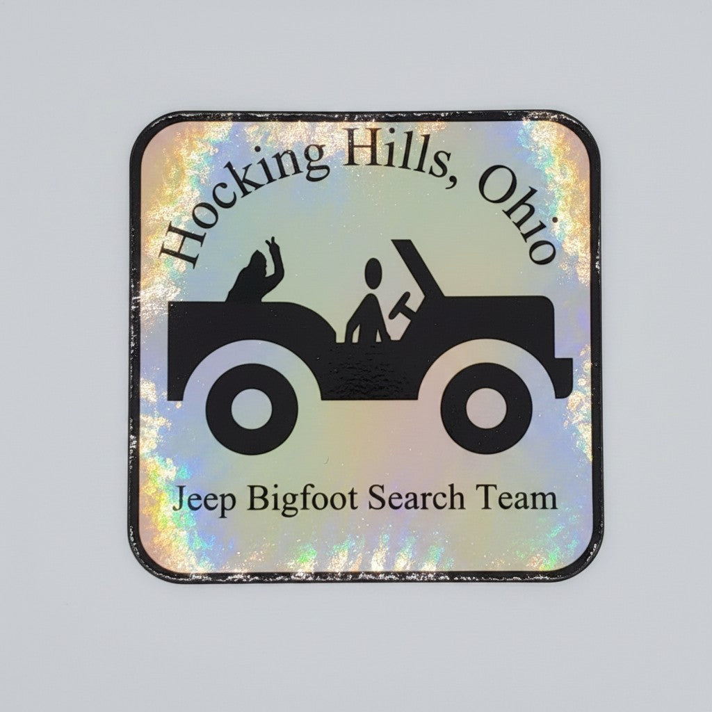 The Hocking Hills Store holographic bumper sticker featuring a black silhouette of a Jeep with two figures and text "Hocking Hills, Ohio Jeep Bigfoot Search Team."