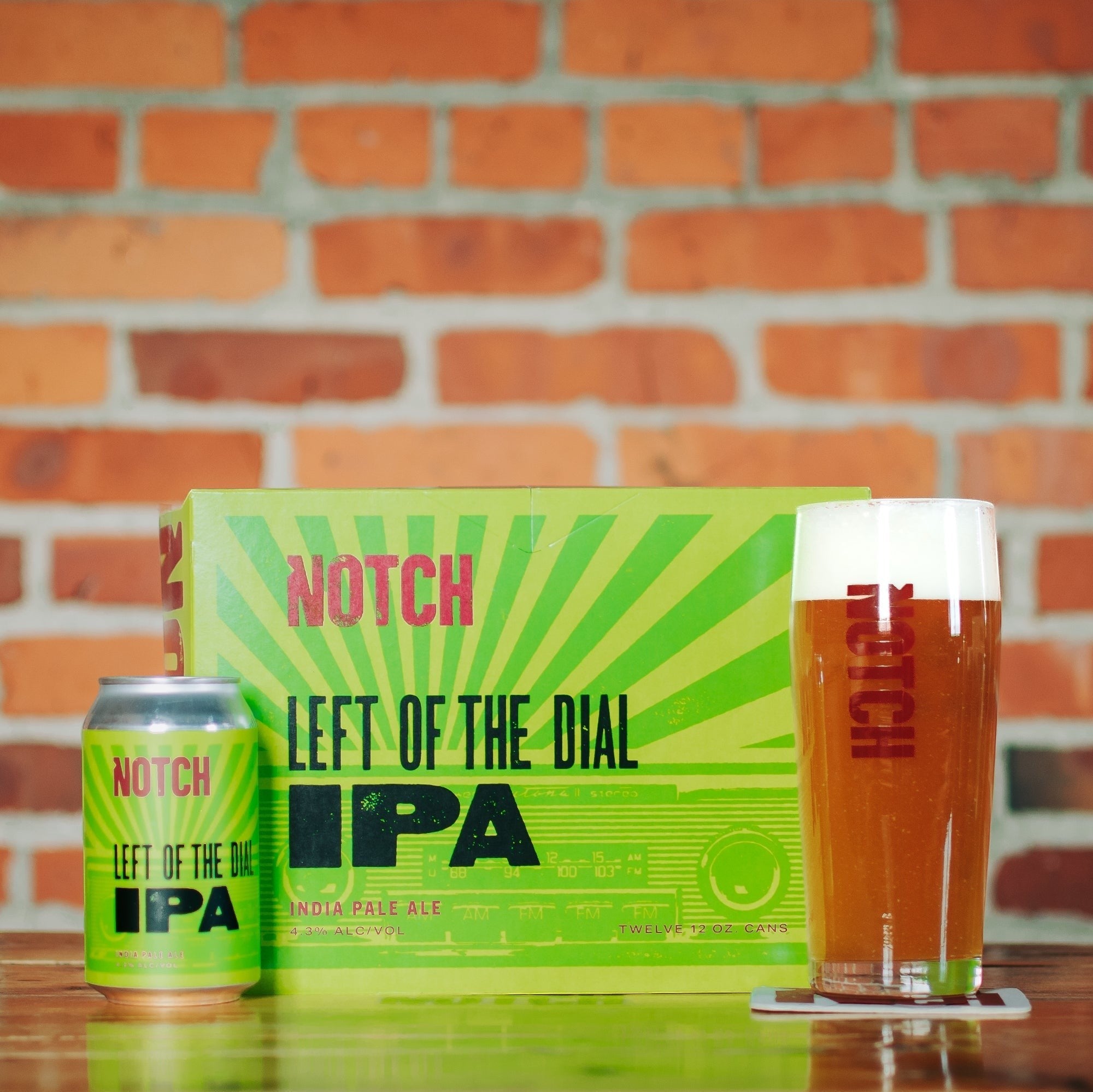 The Hocking Hills Store Left of the Dial IPA beer can and twelve-pack box, with a glass of IPA. The packaging is bright green with pink and black text.