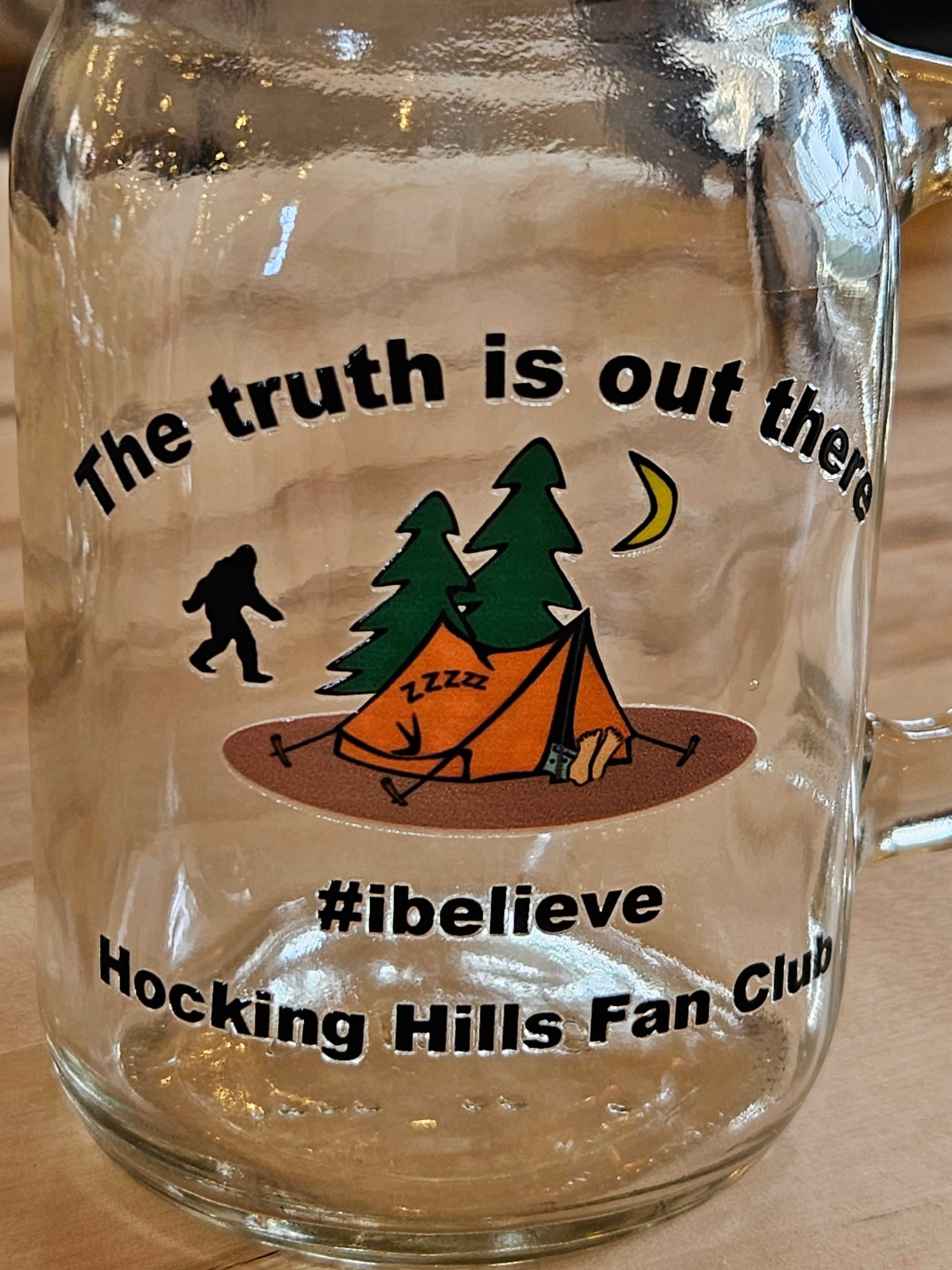 The Hocking Hills Store clear glass mason jar with a Bigfoot, tent, trees, and moon graphic. Text reads "The truth is out there #ibelieve Hocking Hills Fan Club."