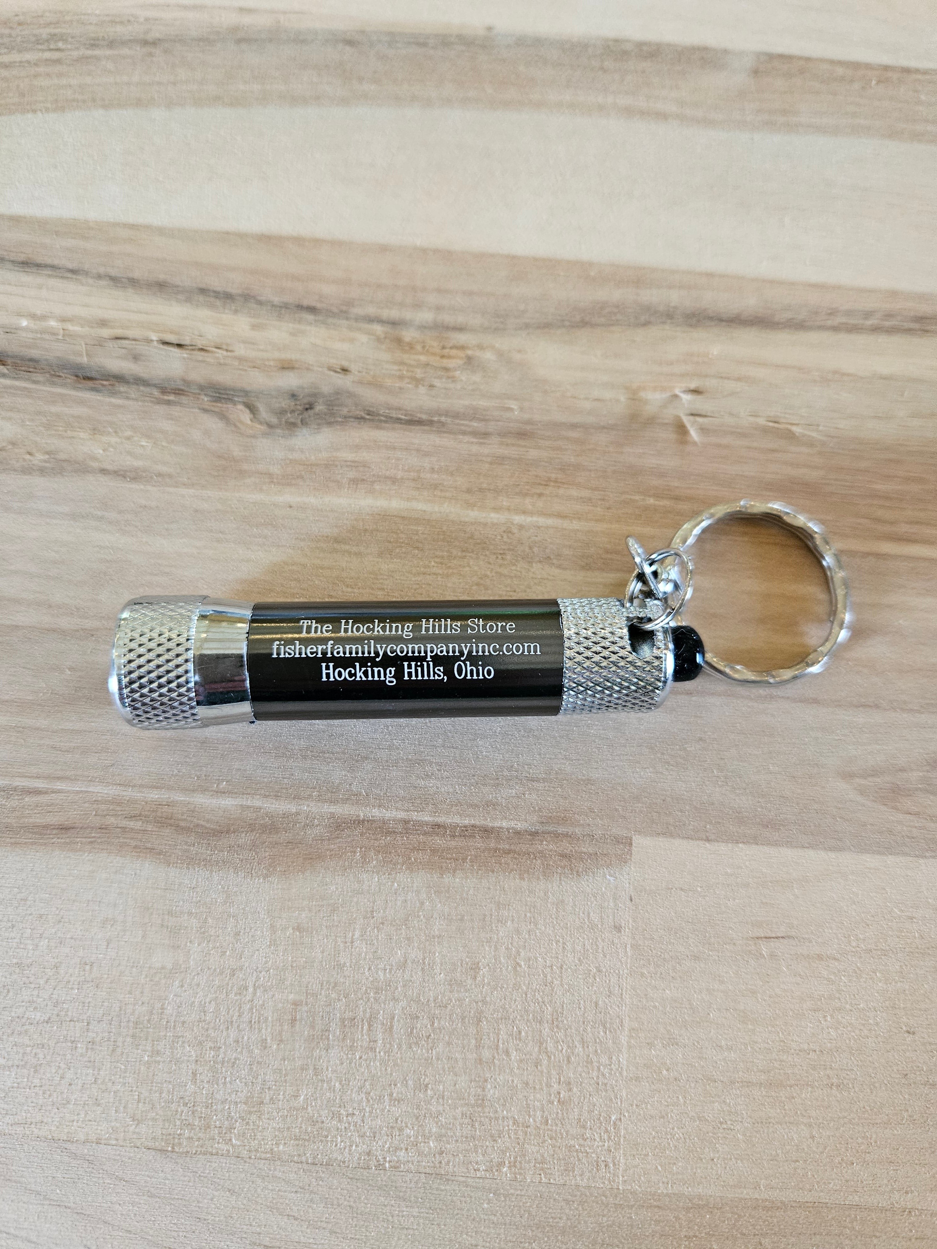 The Hocking Hills Store mini flashlight keychain with silver metal body and black inscription, perfect for Bigfoot enthusiasts.