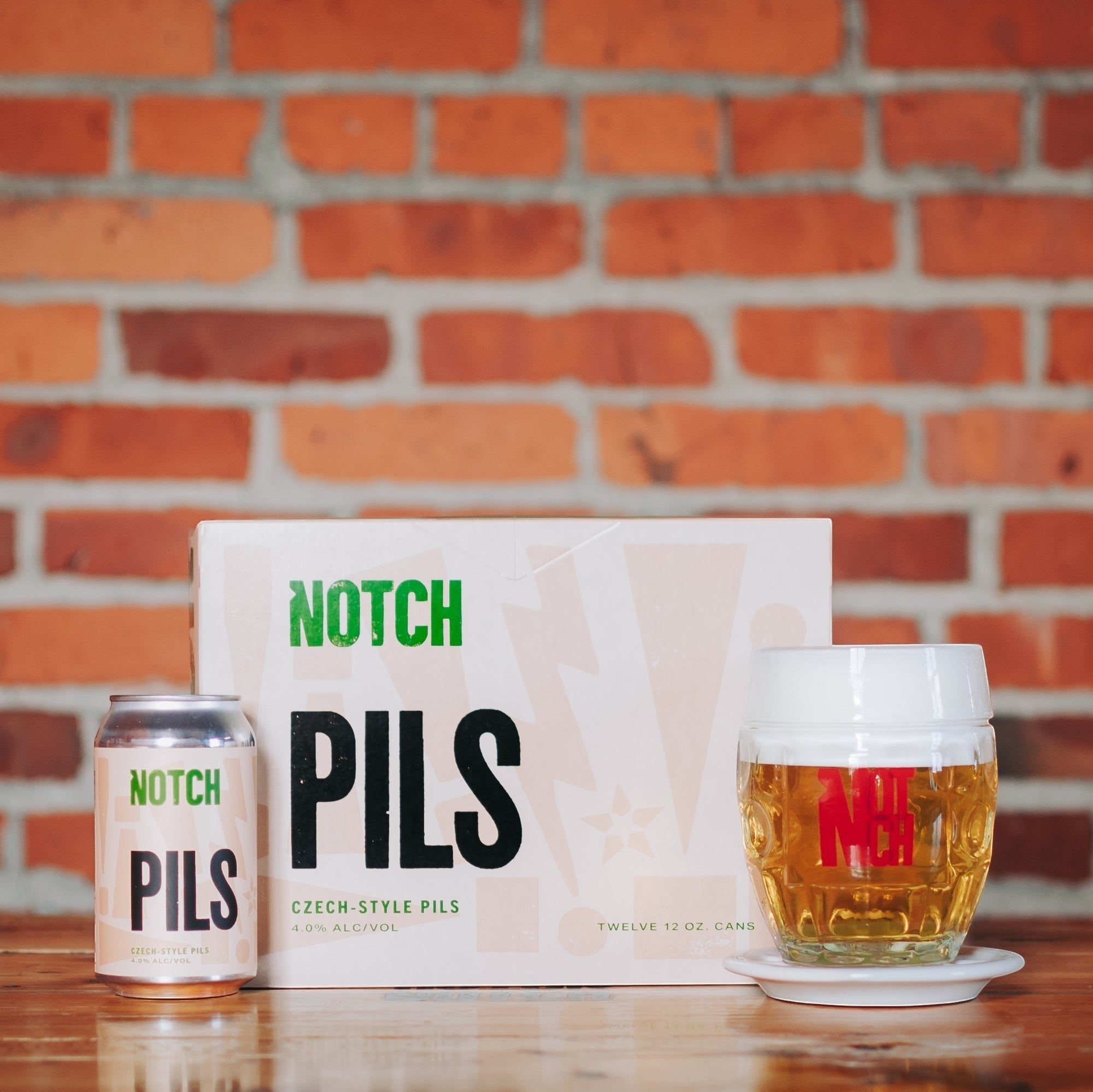 The Hocking Hills Store's Notch Pils Czech-style lager in a can and a glass, with a 12-pack box in the background.