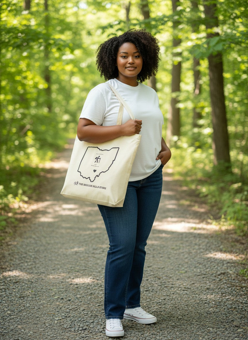 The Hocking Hills Store natural canvas tote bag with a black outline of Ohio, a hiker graphic, and the store name.