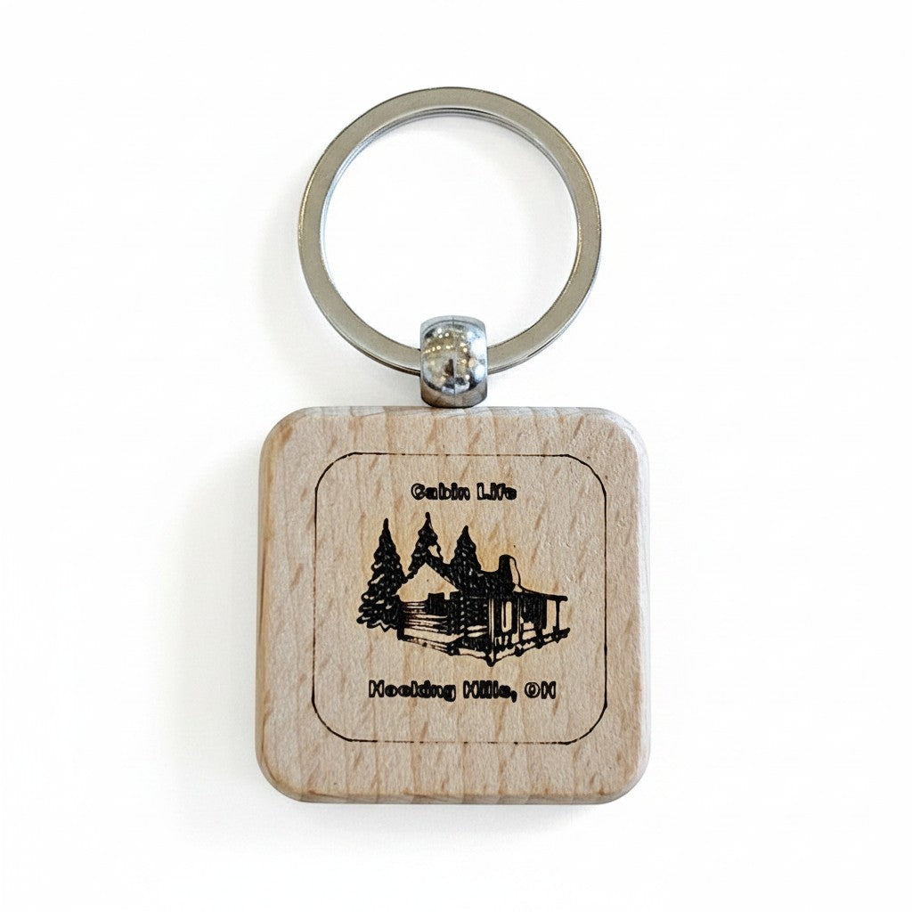 The Hocking Hills Store wooden keychain with laser engraved cabin and trees, reading "Cabin Life" and "Hocking Hills, OH".