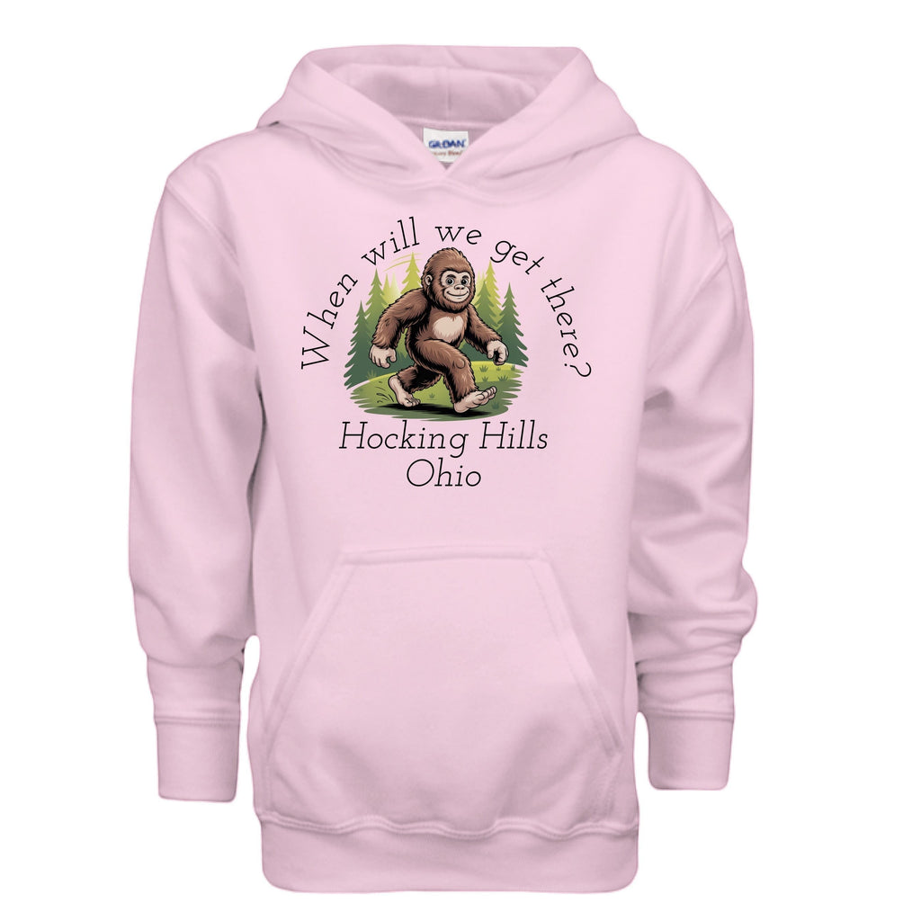 The Hocking Hills Store pink youth hoodie with a Bigfoot graphic and "When Will We Get There? Hocking Hills Ohio" text.