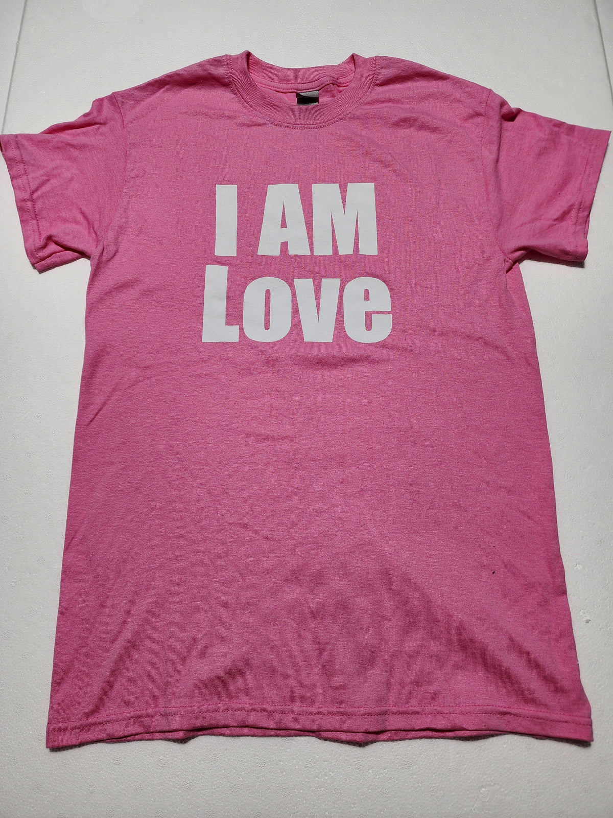 The Hocking Hills Store pink I Am Love graphic t-shirt with bold white minimalist lettering on soft cotton fabric.