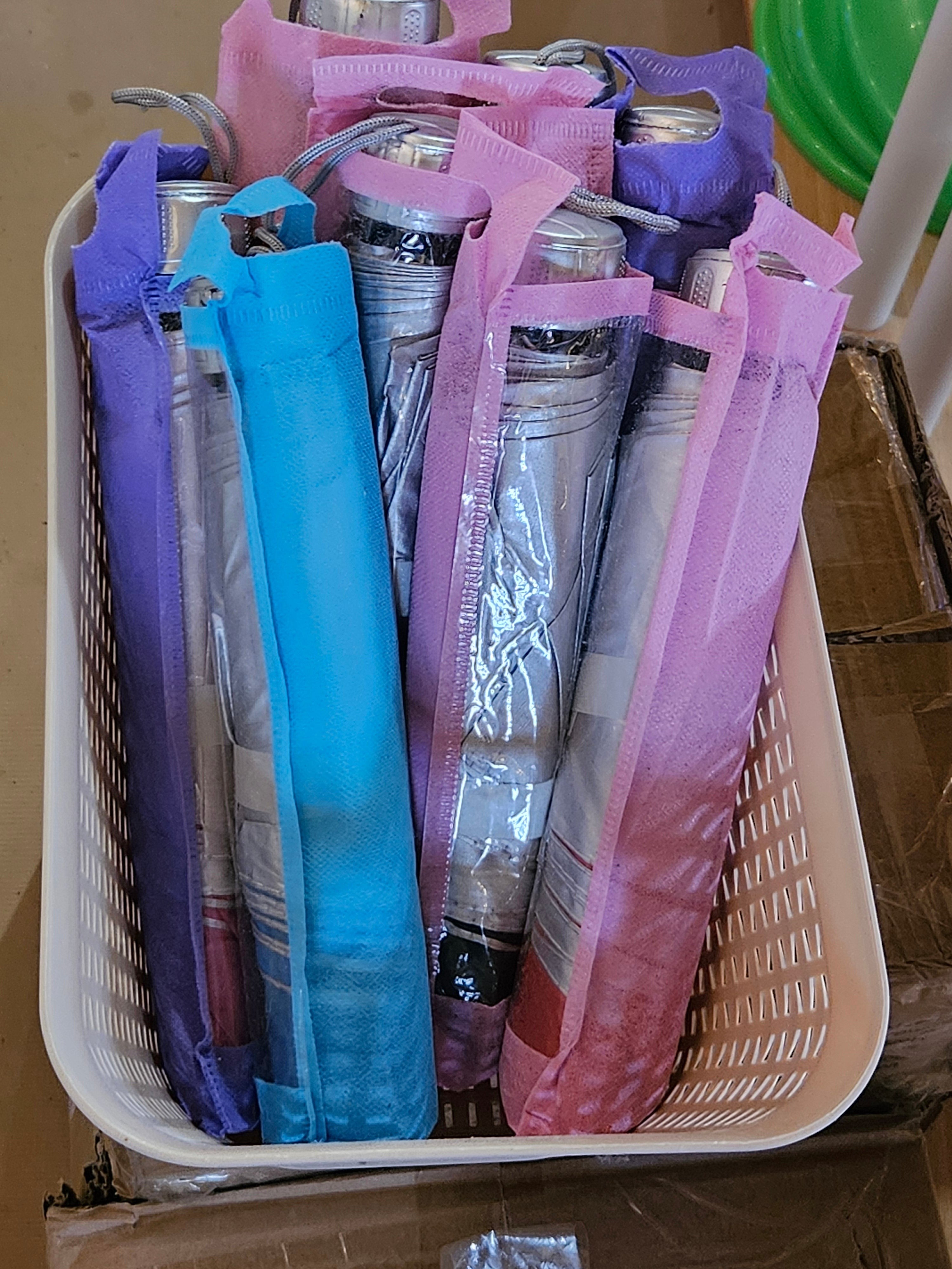 The Hocking Hills Store pocket umbrellas in colorful fabric sleeves stored in a white plastic basket