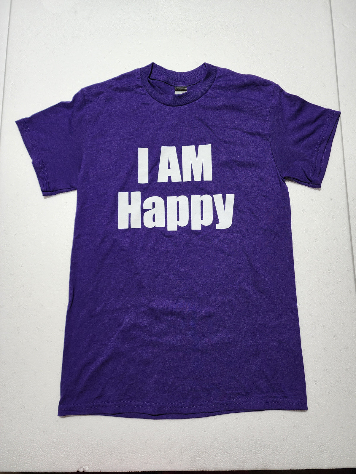 The Hocking Hills Store purple I Am Happy graphic t-shirt with bold white text on a soft cotton fabric