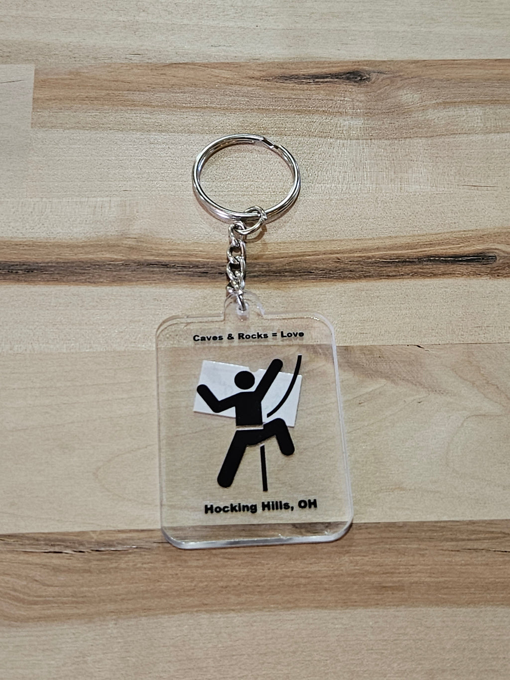 The Hocking Hills Store keychain features a clear acrylic design with a black silhouette of a rock climber and text 'Caves & Rocks = Love' and 'Hocking Hills, OH'.