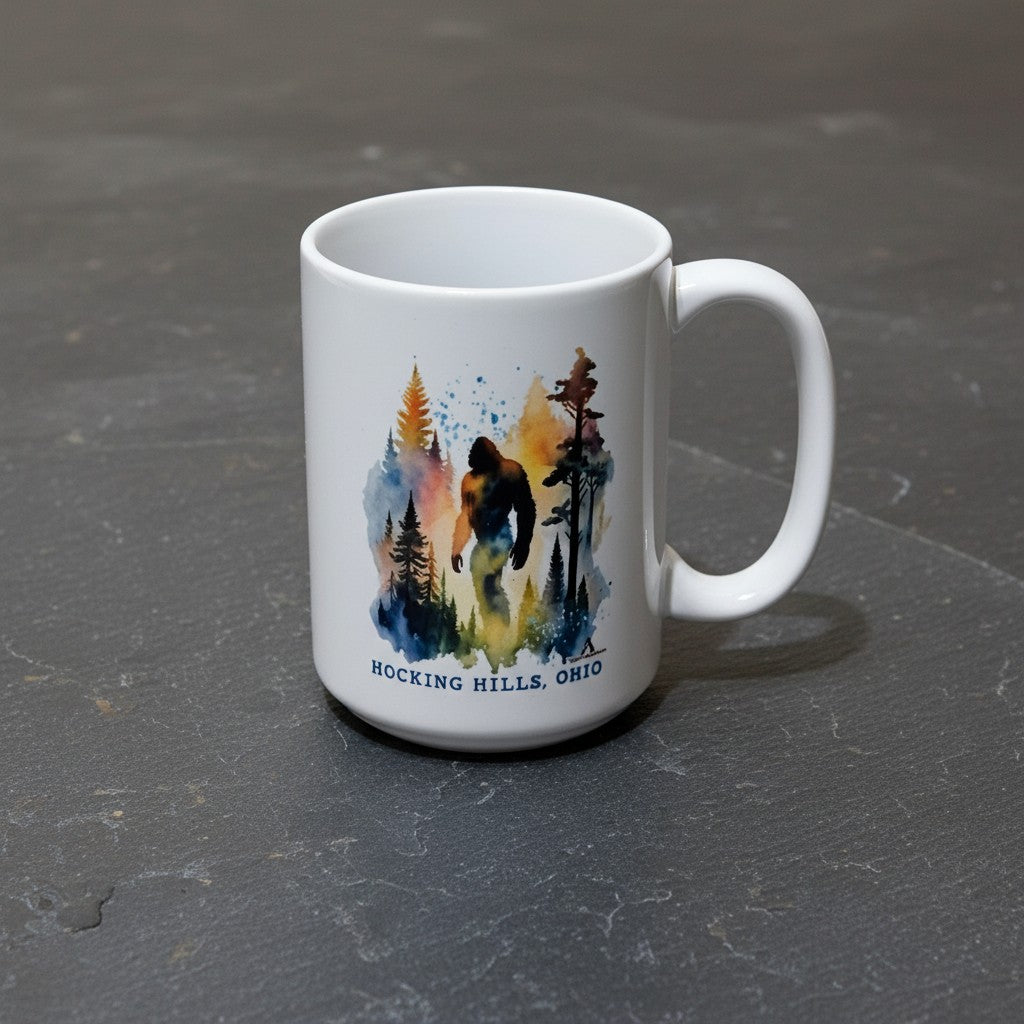 The Hocking Hills Store Sasquatch Big Foot watercolor ceramic coffee mug with forest design.