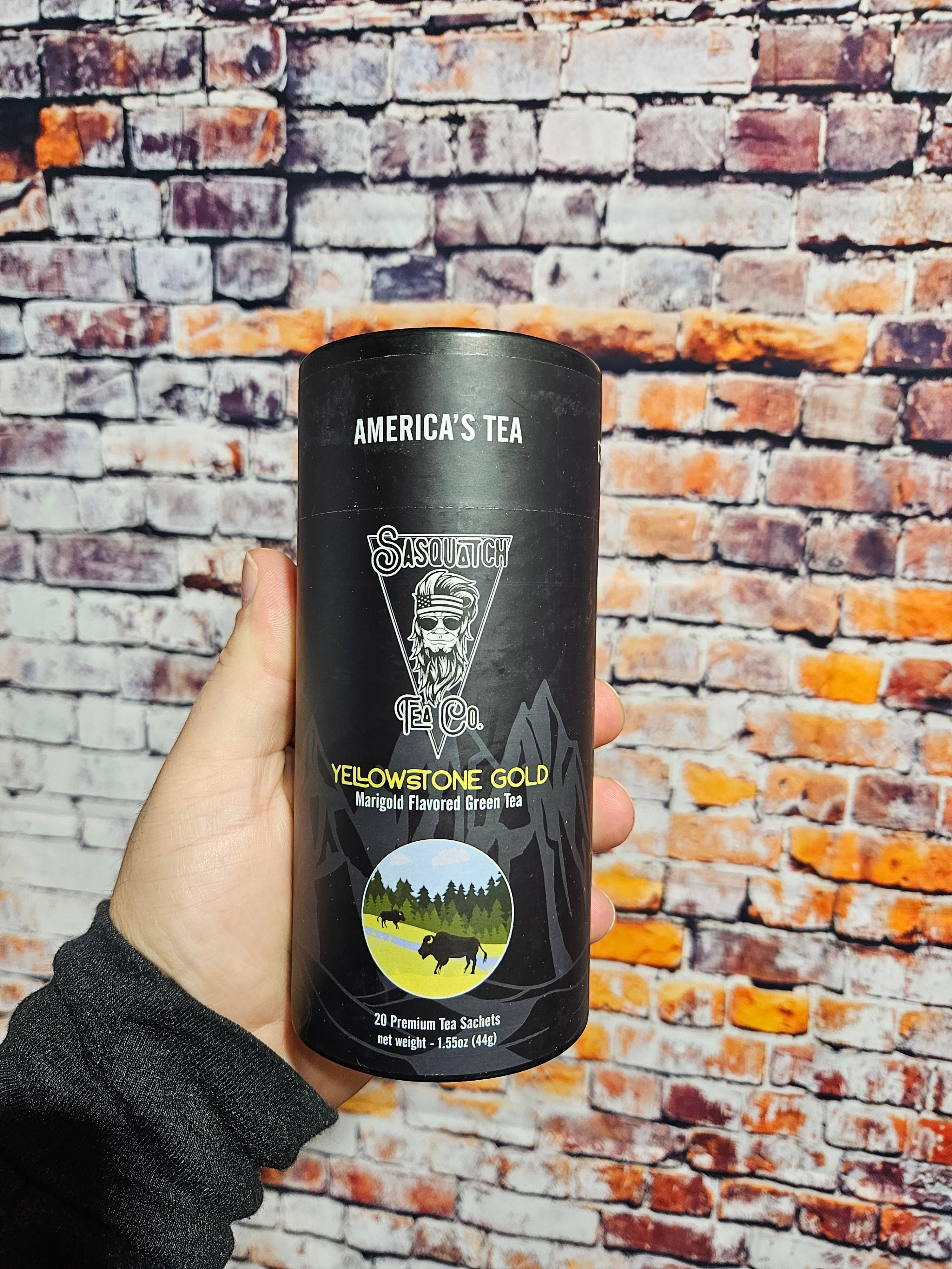 The Hocking Hills Store Sasquatch Tea Yellowstone Gold Marigold Flavored Green Tea in a black cylinder with 20 sachets.