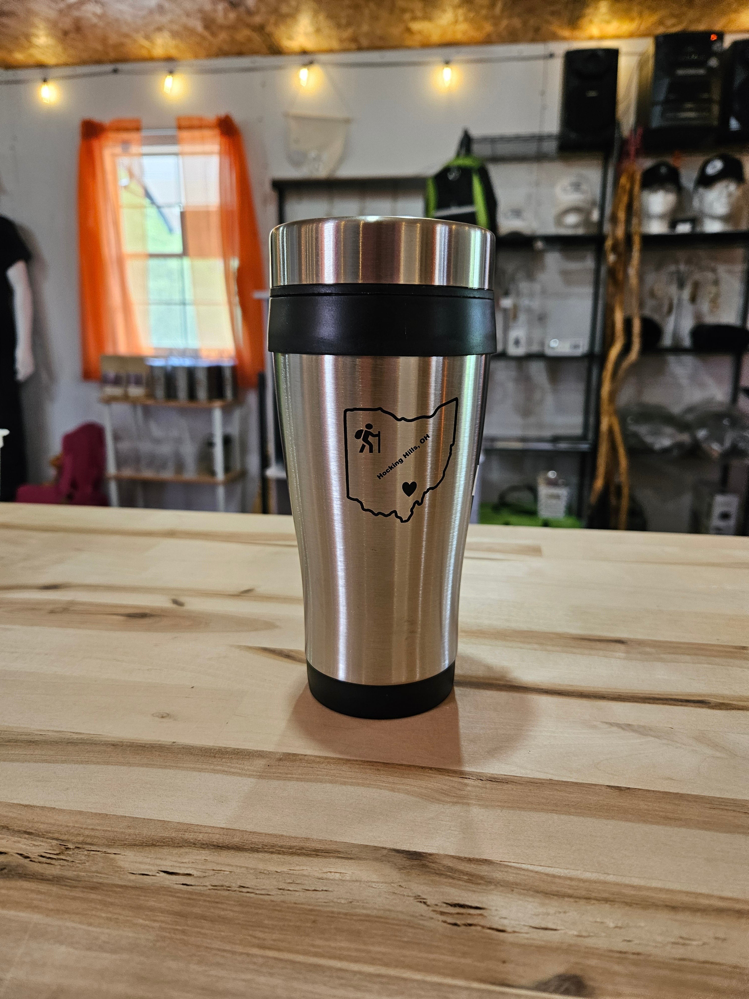 The Hocking Hills Store stainless steel travel mug with black grip and Ohio outline graphic. Perfect for hot or cold beverages.