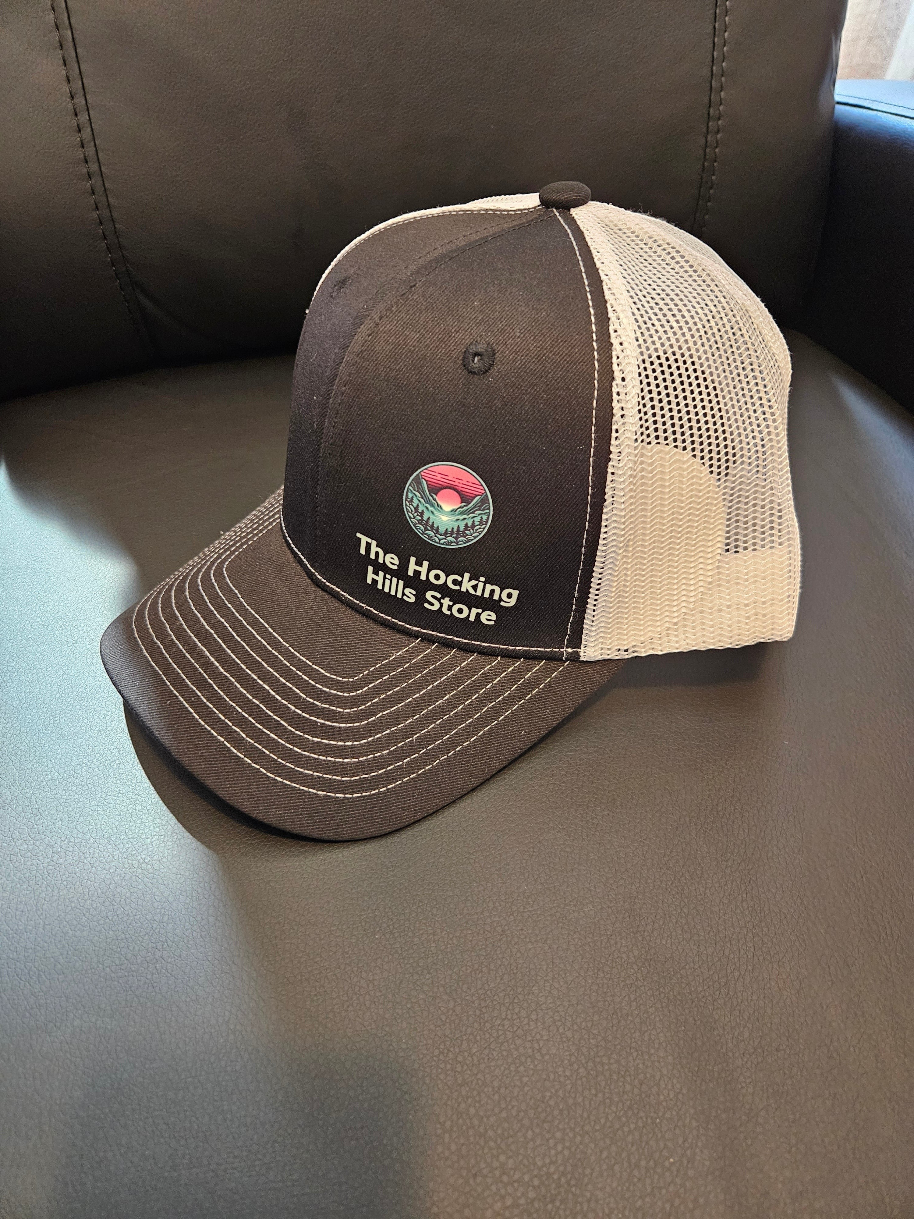 The Hocking Hills Store brown and white trucker hat with embroidered logo, adjustable strap for comfortable fit.