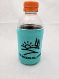 The Hocking Hills Store turquoise can cooler with black logo featuring sun and trees. Fits a standard bottle.