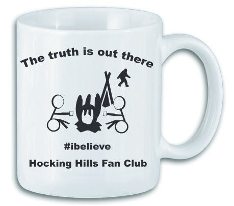 The Hocking Hills Store white ceramic mug with black text and graphics featuring a campfire, tent, Bigfoot, and the phrase "The truth is out there #ibelieve Hocking Hills Fan Club".
