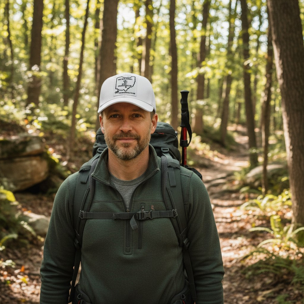 The Hocking Hills Store white baseball cap with a patch featuring Ohio and hiking imagery. Adjustable strap.