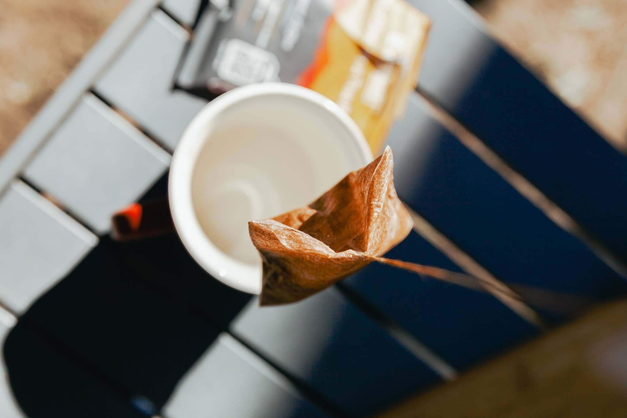 The Hocking Hills Store Wildland Coffee extra dark roast steepable coffee bag in a white mug outdoors.