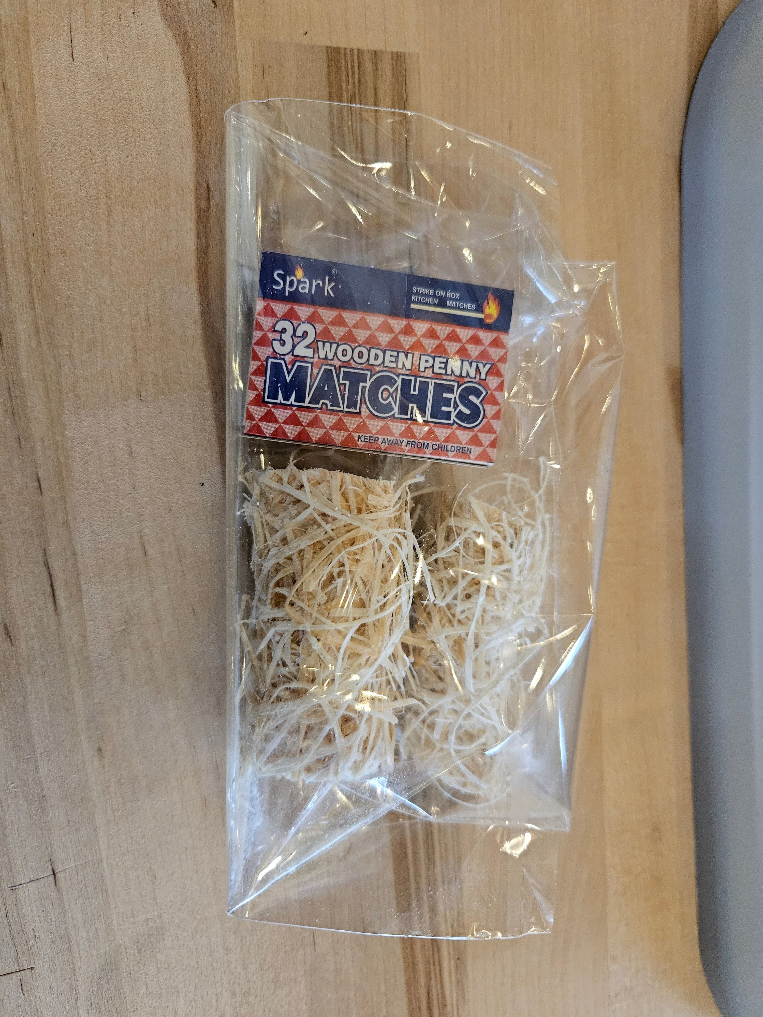 The Hocking Hills Store Spark 32 wooden penny matches in a clear plastic package with wood shavings.