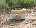 The Hocking Hills Store handmade wooden toy camera for kids, light blue and natural wood finish, with rotating lens and shutter button.