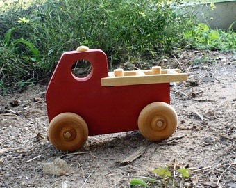 The Hocking Hills Store handmade wooden toy fire truck, red with natural wood wheels and bed detail. Perfect for imaginative play.